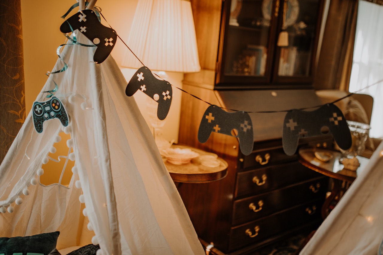 Teepee canopy styled with black game controller cutout bunting garland and warm lighting
