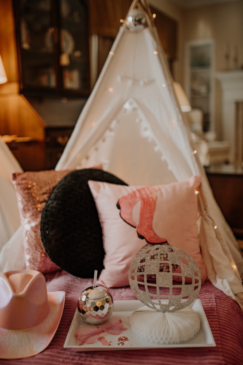 Vertical view inside styled teepee with fairy lights, disco topper, and plush bedding
