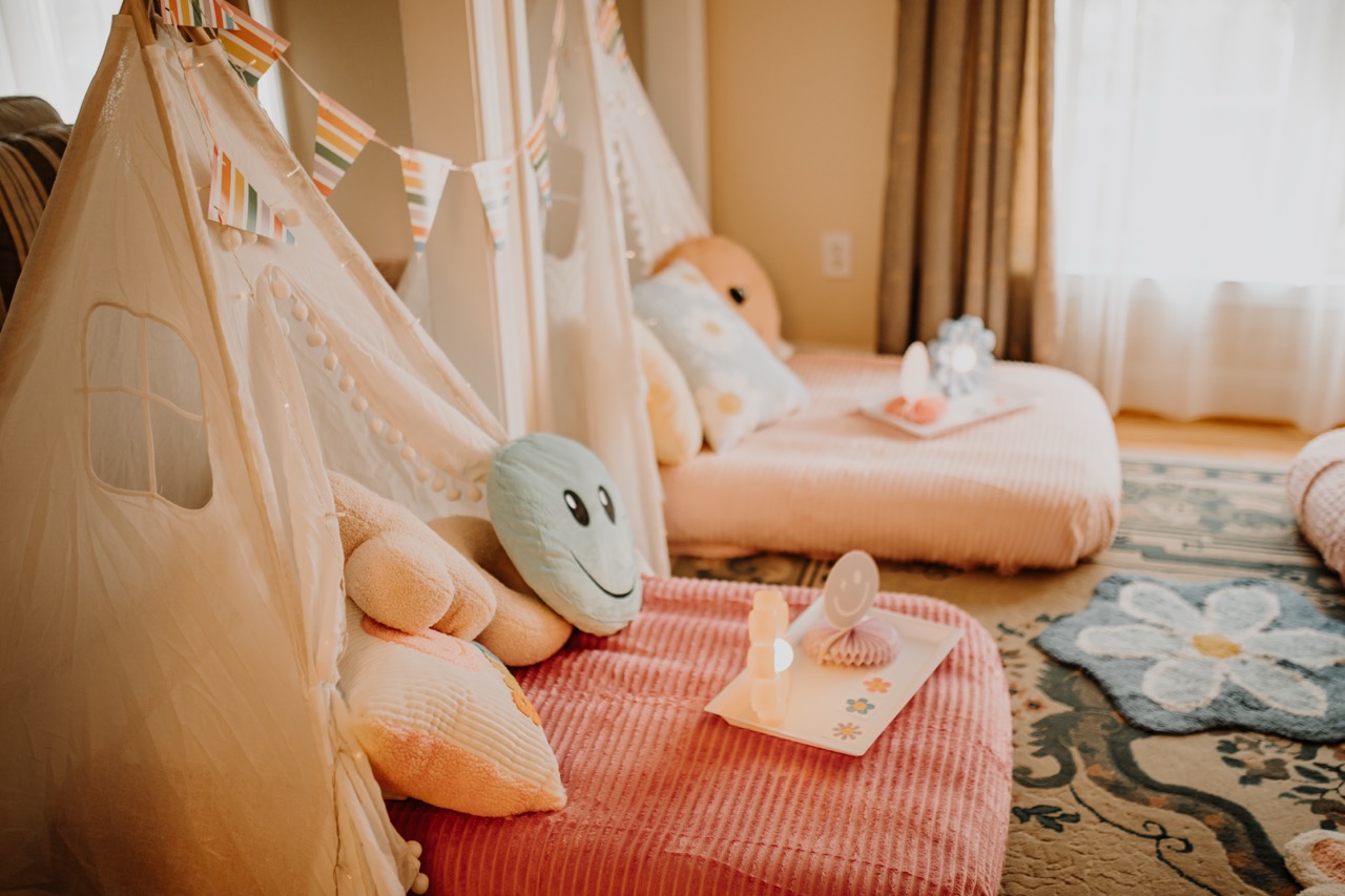 Side perspective of Flower Power sleepover teepees with window cutout, tray lights, and daisy rug