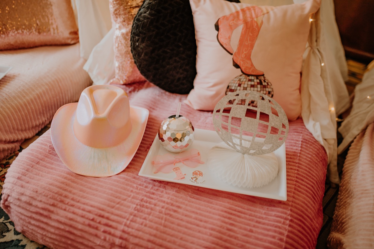 Styling tray with cowgirl boot pillow, holographic hat, disco tumbler, and heart glasses