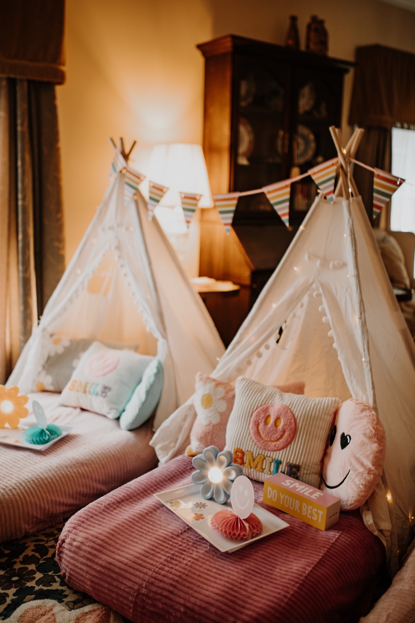 Warm ambient glow over Flower Power teepee row with personalized tray decor and bunting