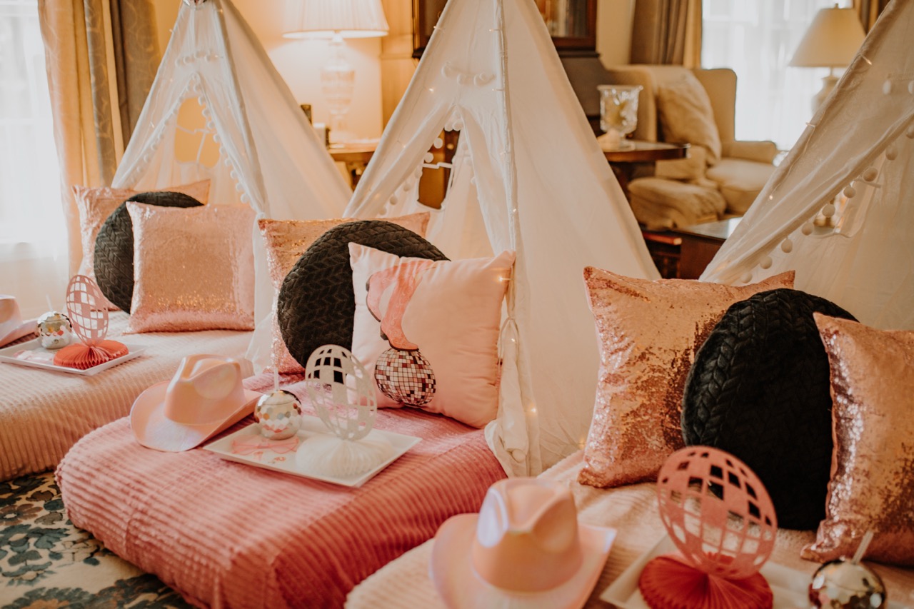 Disco Cowgirl themed teepee sleepover with pink bedding, disco ball decor, and cowgirl hats