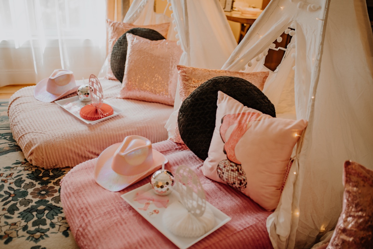 Sunlit room with two styled sleepover teepees and shimmering pink cushions