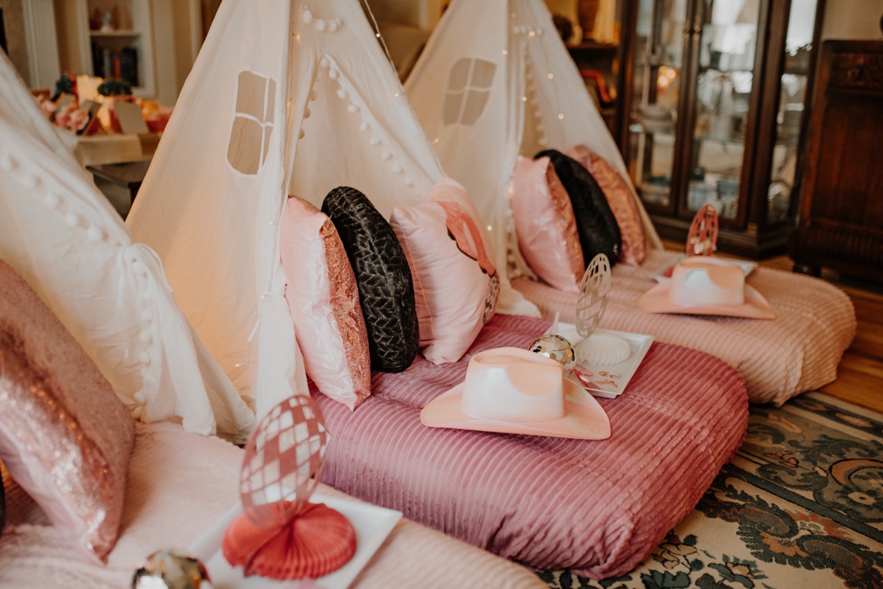 Three cozy teepees in a row with pink plush mattresses and cowgirl hats