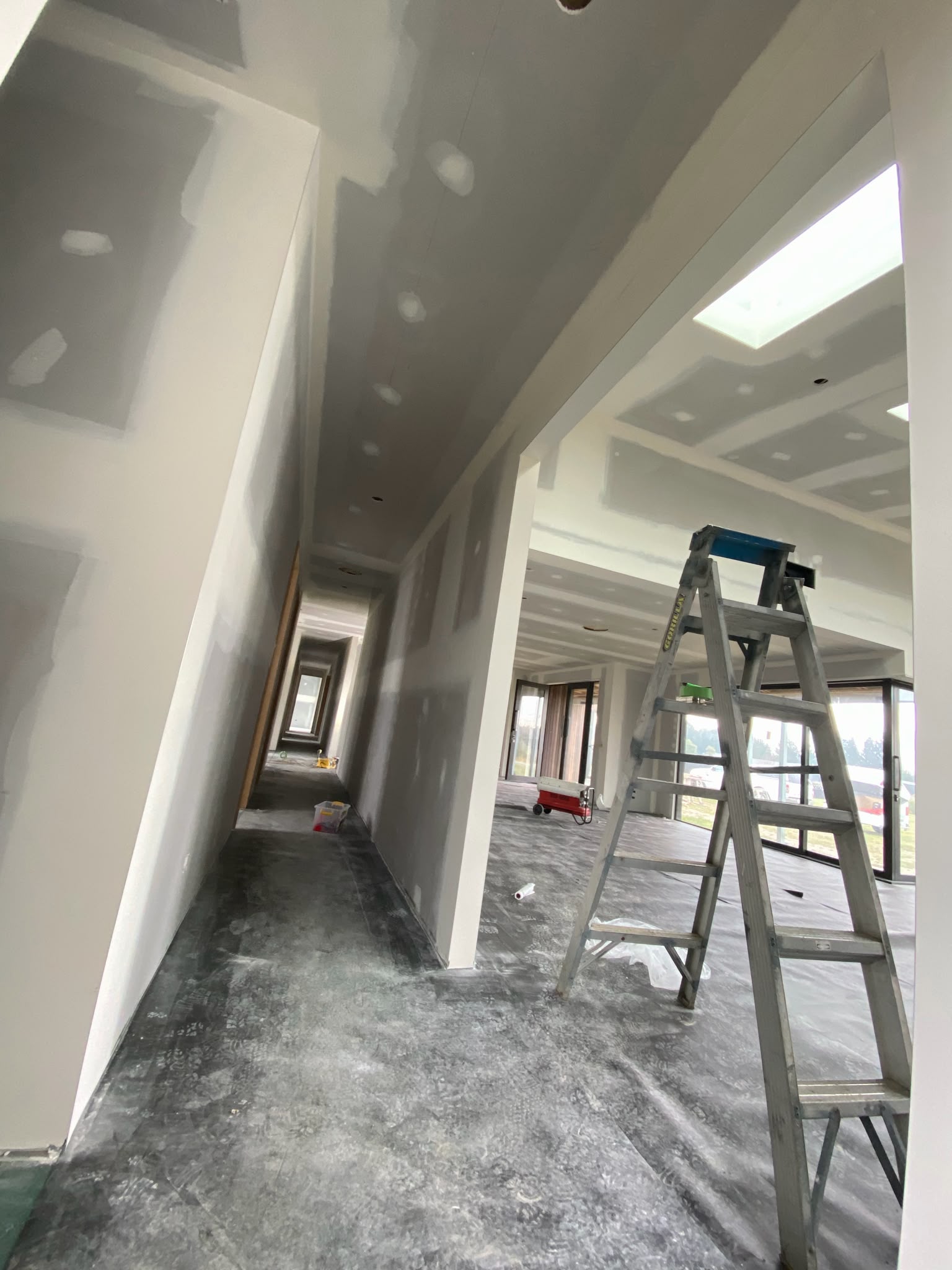 Interior plastering and stopping preparation across hallway and high ceilings on site