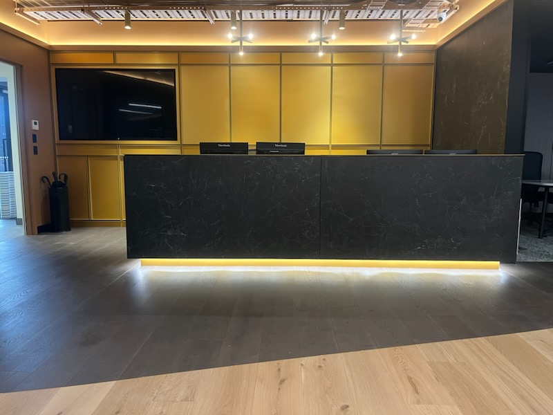 Luxury commercial reception counter with warm brass panelling and linear LED illumination completed by Garden City Painters