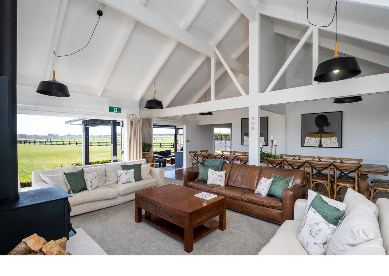 Soaring vaulted ceiling living room with woodburner fireplace and plush couches
