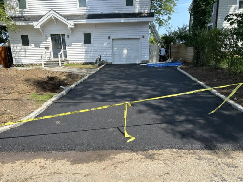 Freshly paved asphalt driveway with hand-set Belgian block stone border edging
