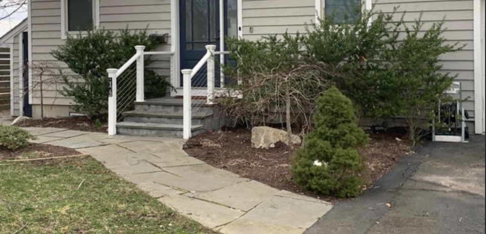 Front flagstone walkway and entrance steps before renovation: uneven stones and overgrown bushes