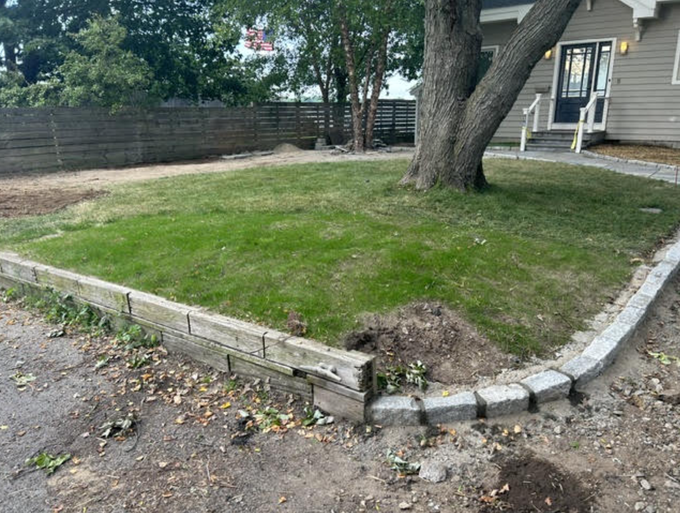Deteriorated wooden retaining wall along the lawn edge before replacement