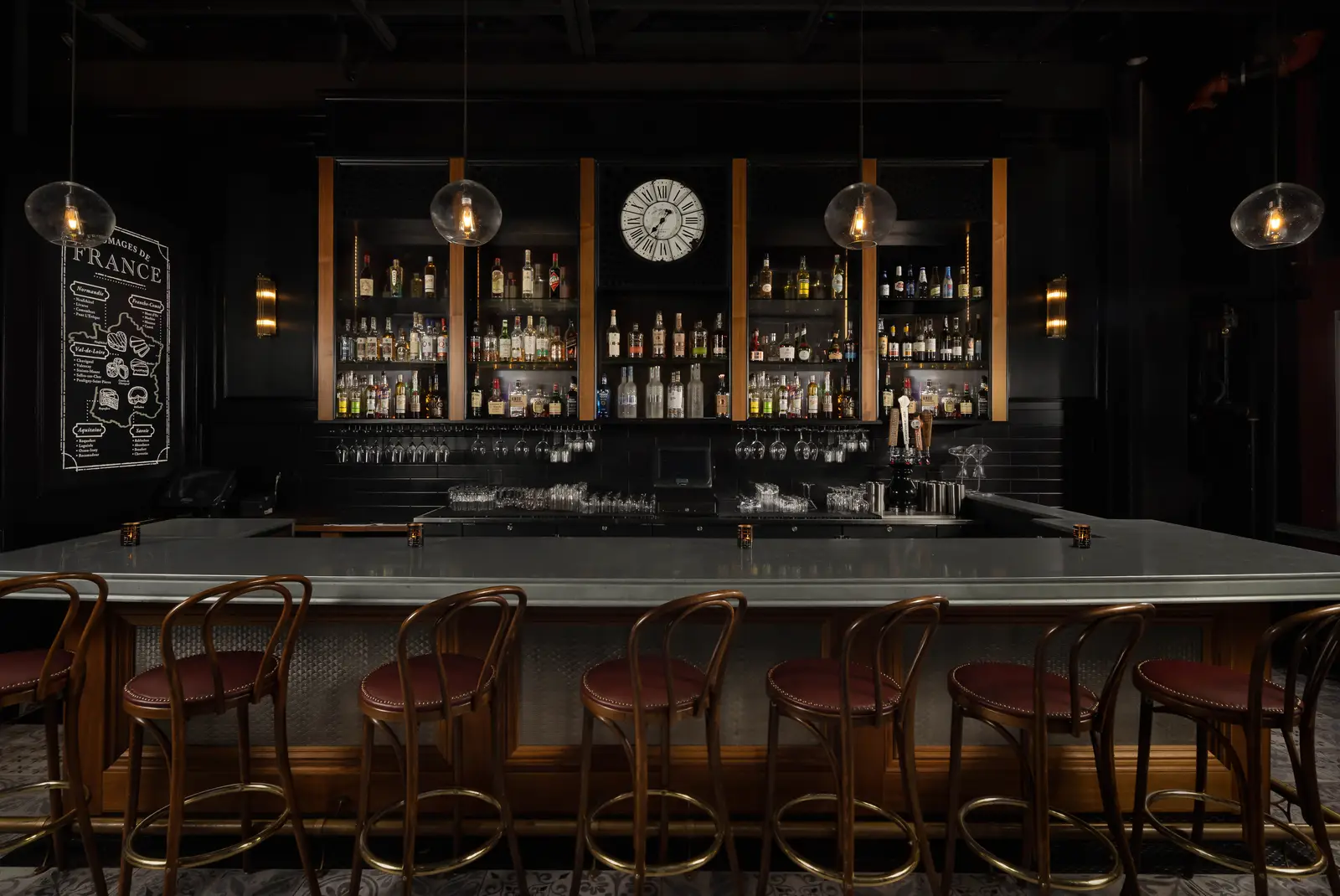 Et Voilà French Bistro full zinc bar with illuminated spirits, vintage French clock, and leather barstools on Adams Avenue in San Diego
