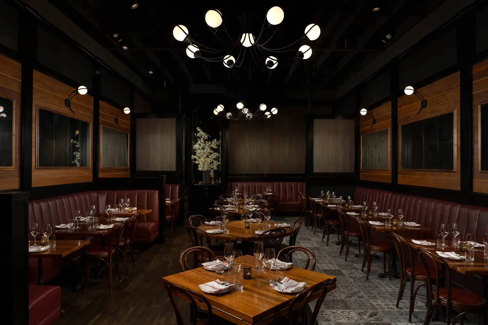 Et Voilà French Bistro authentic dining room with leather banquettes, wooden tables, and chandelier illumination in San Diego