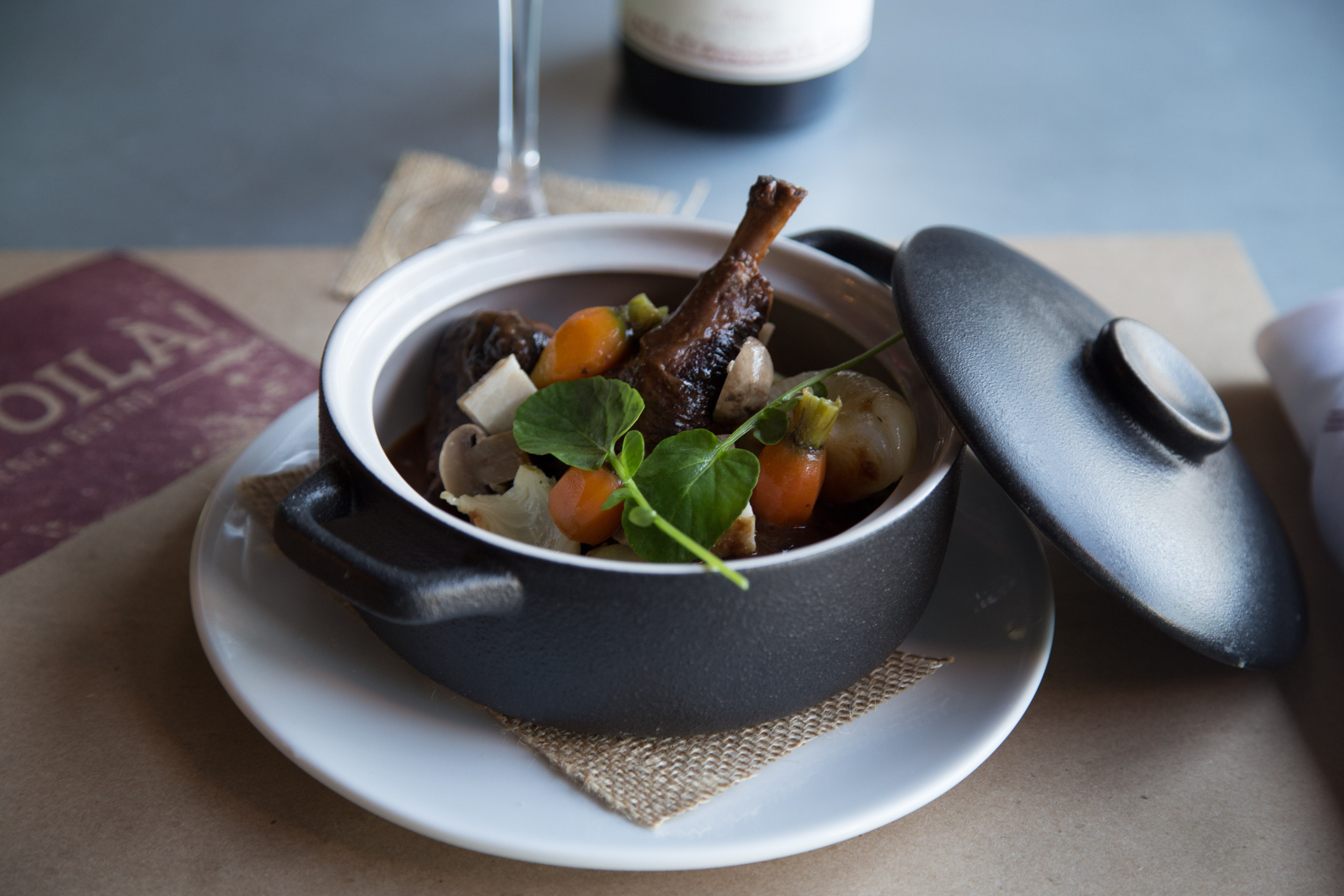 Traditional Coq au Vin braised chicken leg in cast iron cocotte with Burgundy wine reduction at Et Voilà French Bistro