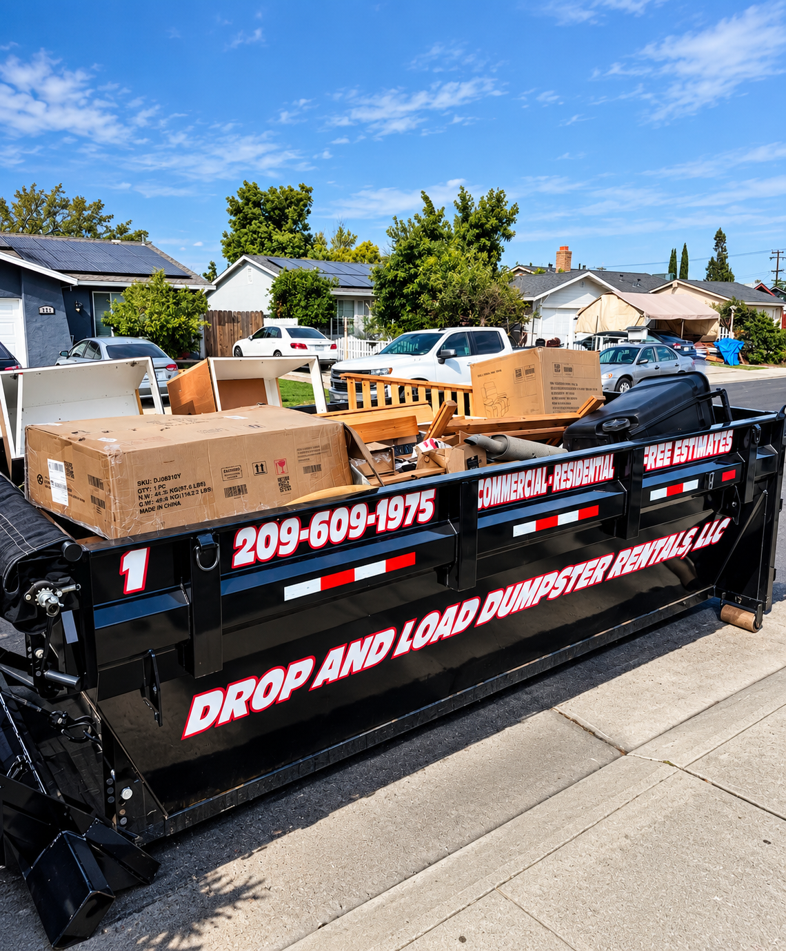 Drop And Load roll-off dumpster trailer loaded with cleanout debris in residential neighborhood