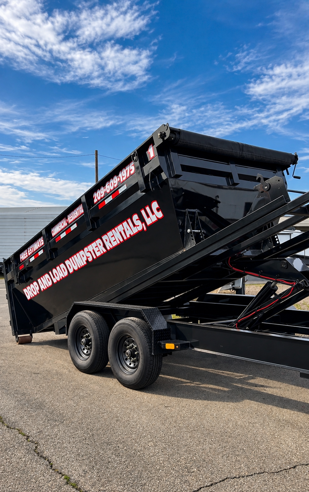 Drop And Load heavy-duty black roll-off dumpster trailer loaded on hydraulic tilt bed