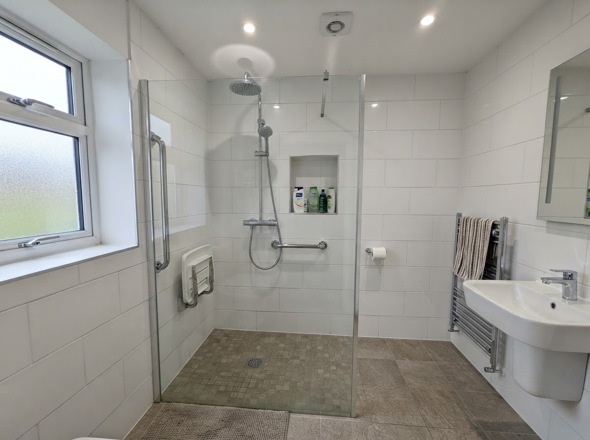 A completed accessible walk-in shower with grab rails, slip-resistant floor and fold-down seat
