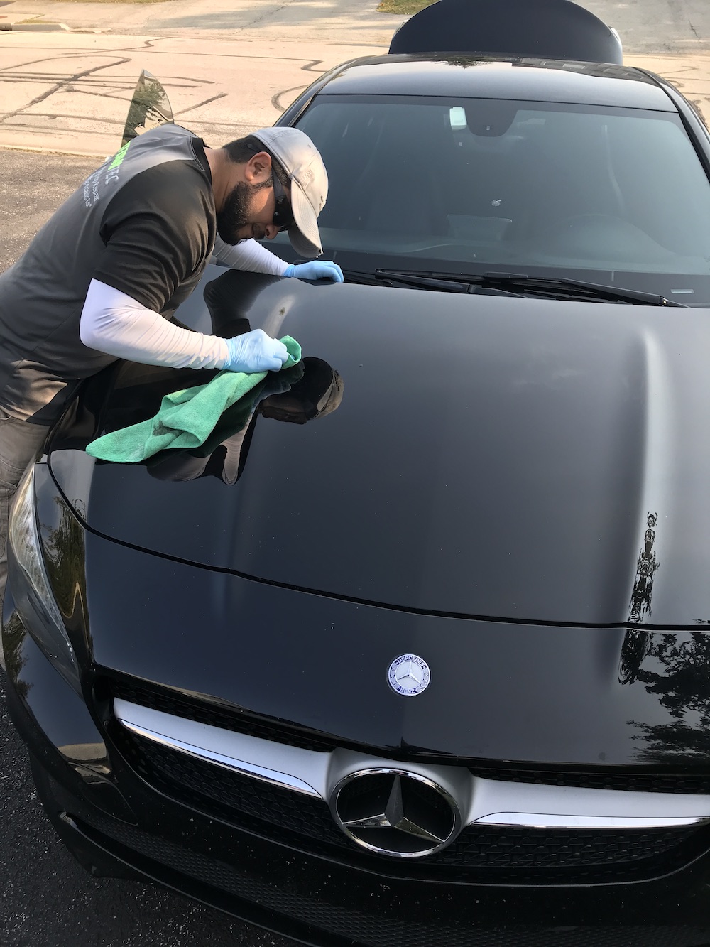 Exteriortec specialist detailing and polishing a black Mercedes-Benz hood on site
