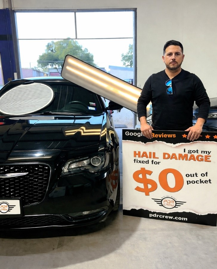Driver with repaired black Chrysler and $0 out of pocket hail damage guarantee