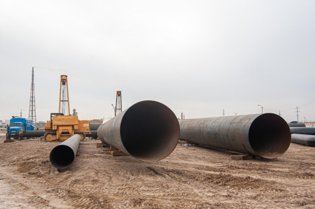 Staged large-diameter pipeline in a Fort McMurray yard