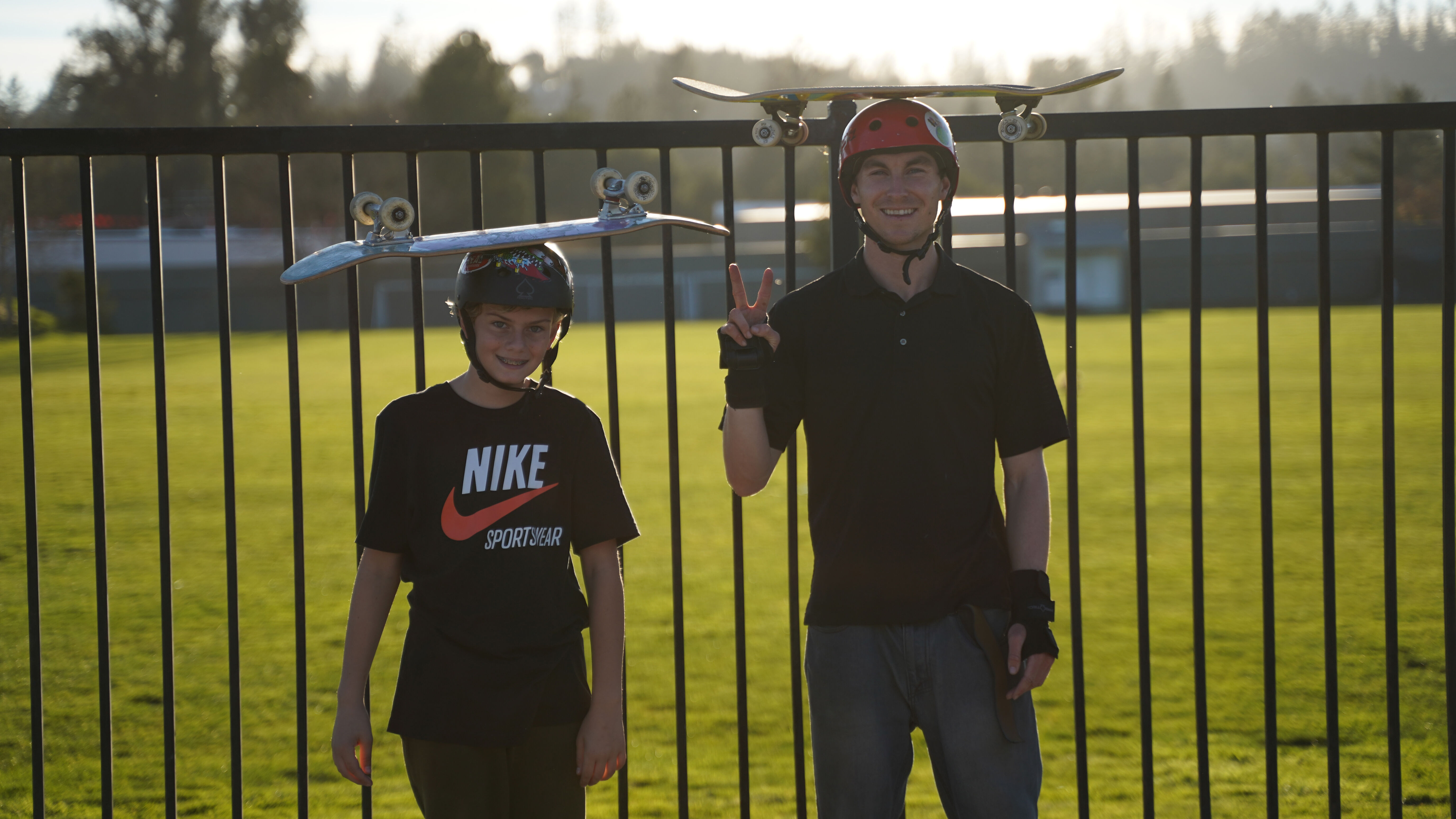 Luke and student balancing skateboards on their helmets with stoked smiles