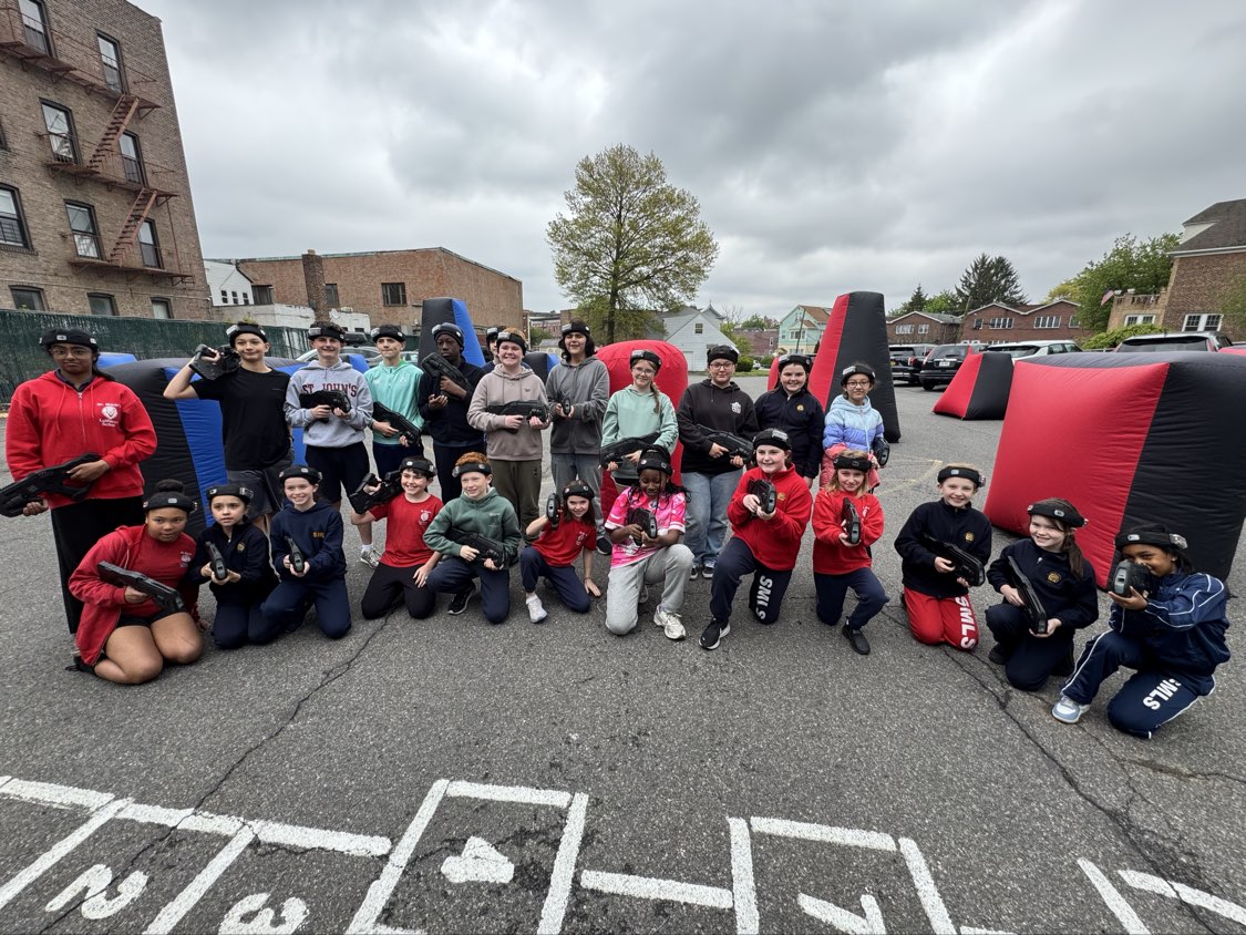 Large community and corporate group holding blasters and wearing sensor headbands at a mobile outdoor laser tag arena