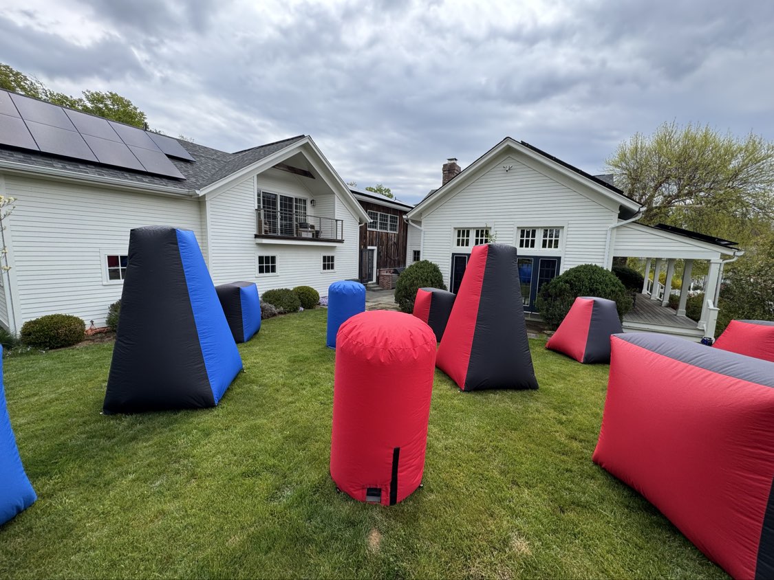 Inflatable Bunkers — outdoor backyard mobile laser tag playing area with red, blue and black inflatable bunkers on grass
