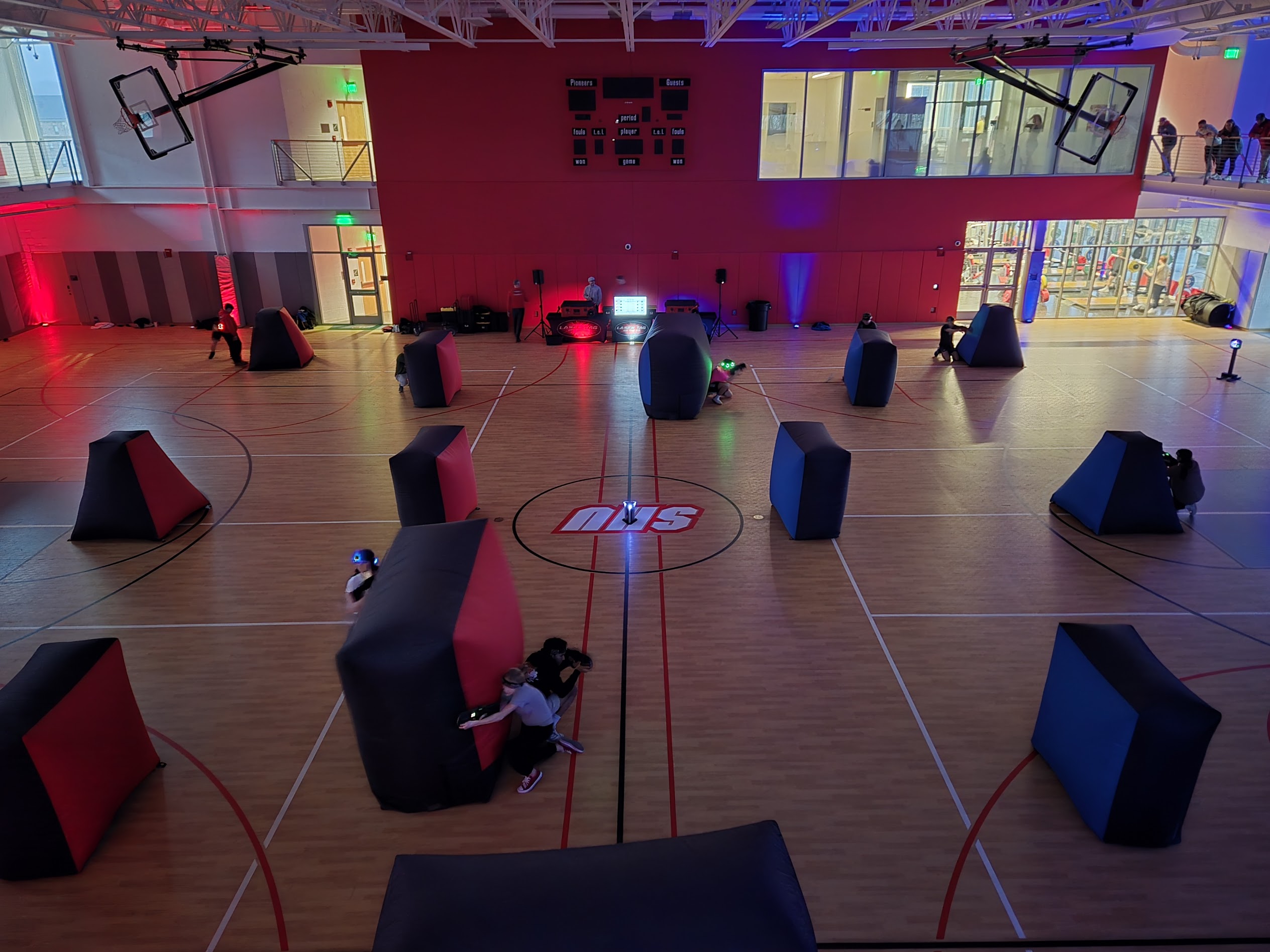 School gymnasium laser tag event in action with students playing, Game Coach table and illuminated bunkers