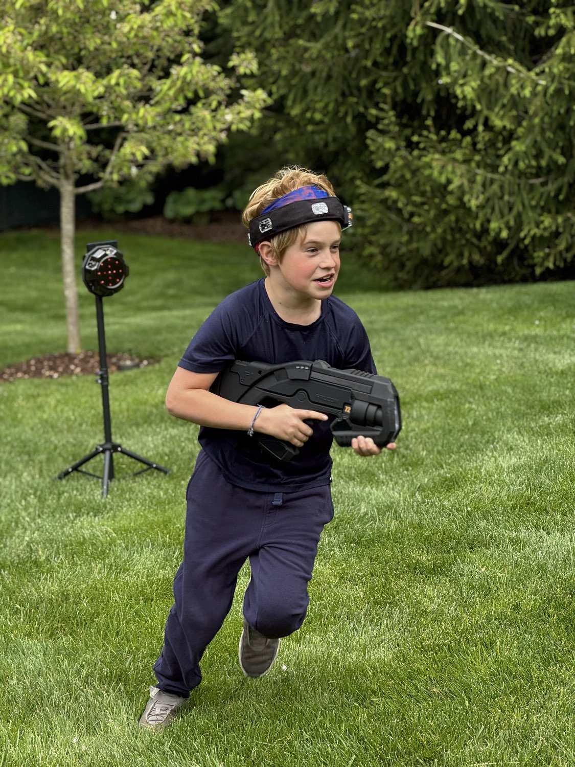 Laser tag player in action beside an interactive target box at an outdoor birthday party
