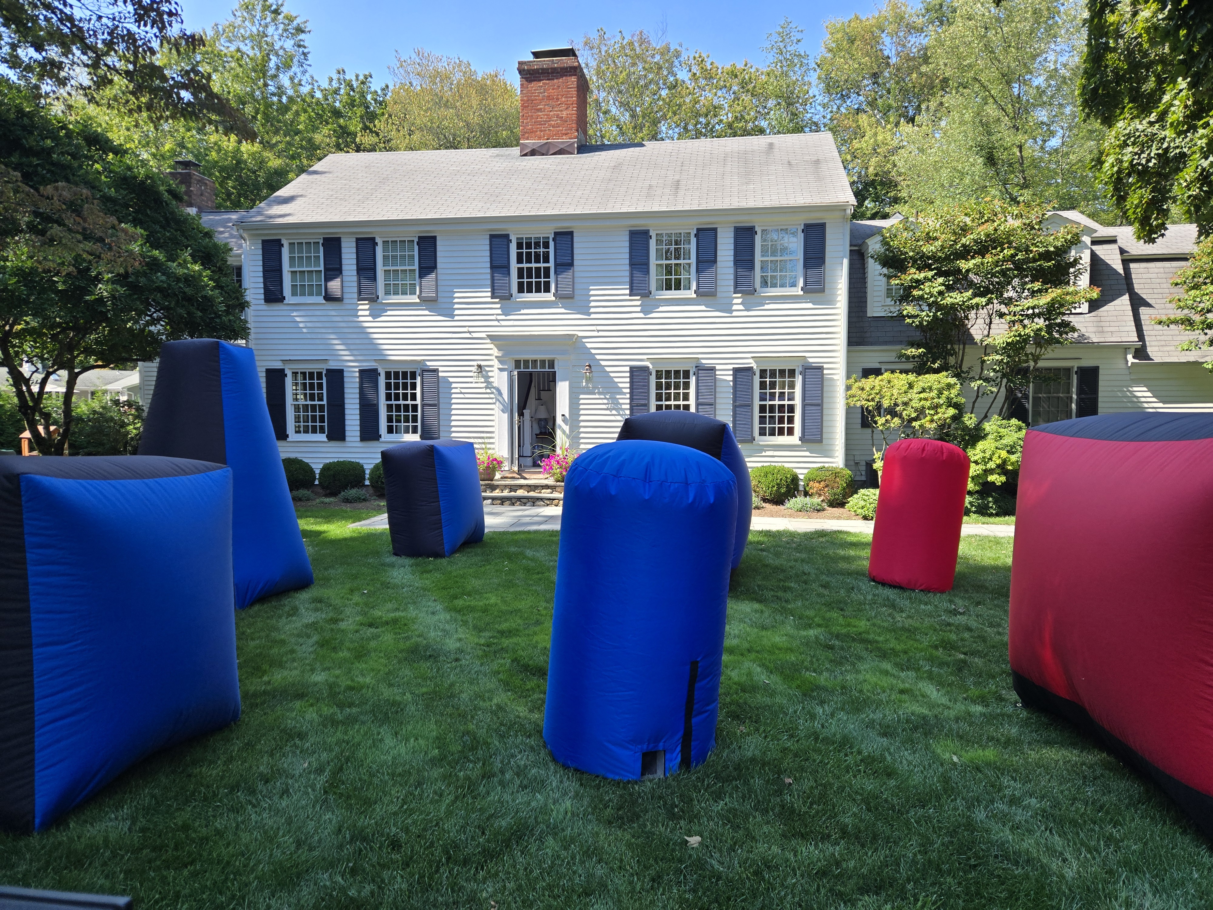 Inflatable Bunkers — red, blue and black inflatable bunkers set up on a manicured residential lawn