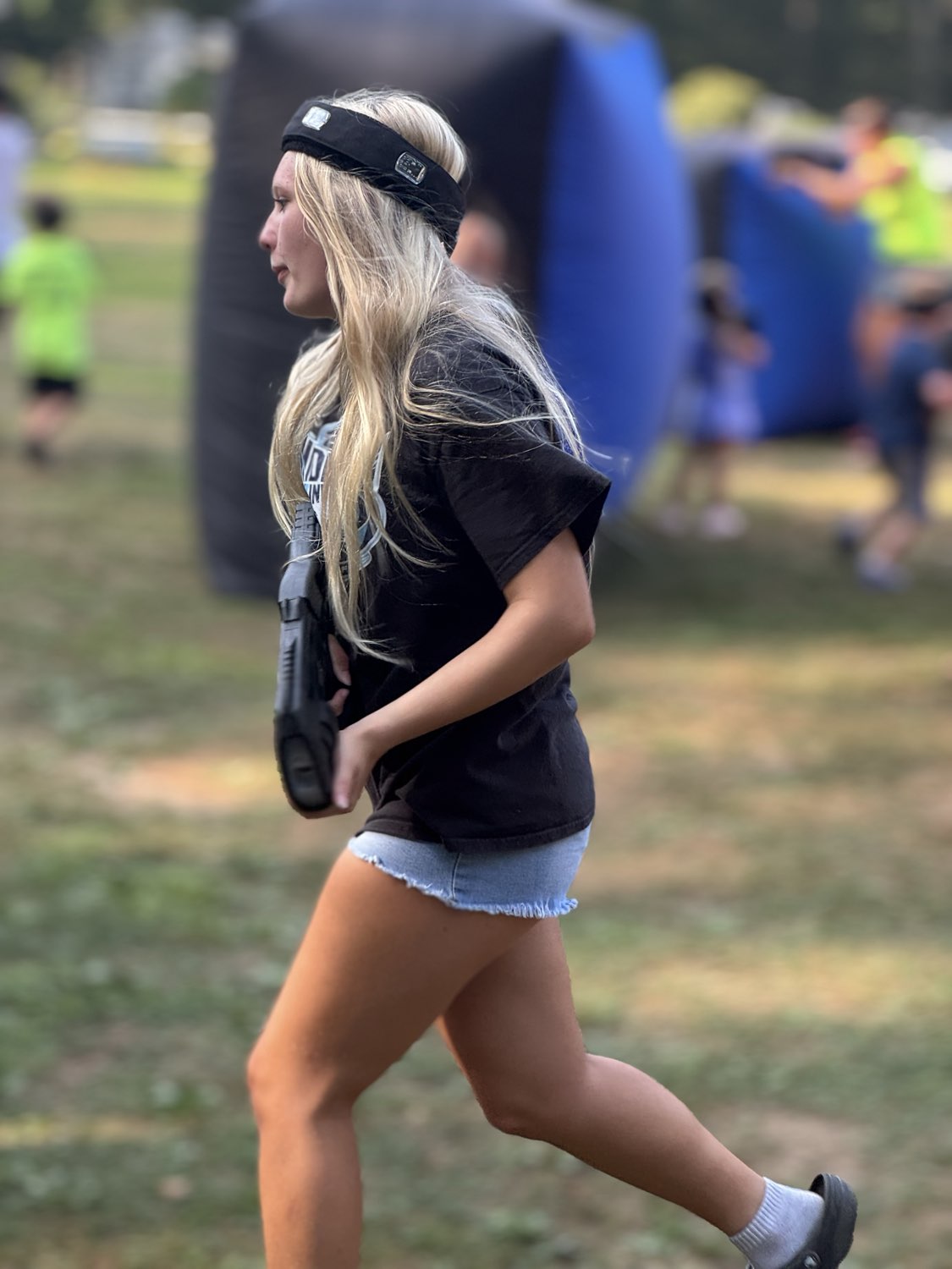 Player in action with blaster and sensor headband at an outdoor laser tag event