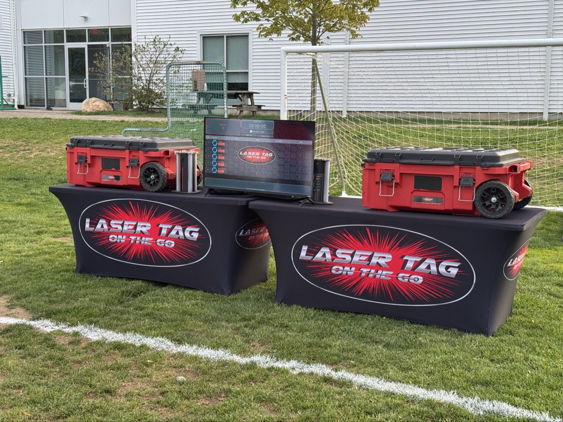 Laser Tag On The Go Setup — outdoor event scoreboard display and equipment cases on branded tables