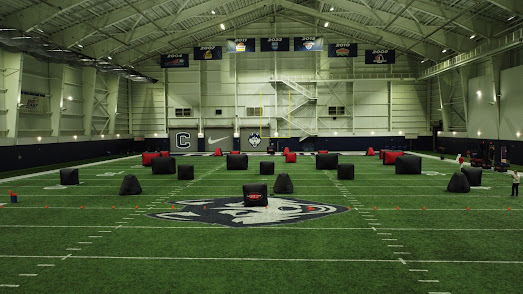 Large indoor turf facility setup with Laser Tag On The Go inflatable bunkers across the field