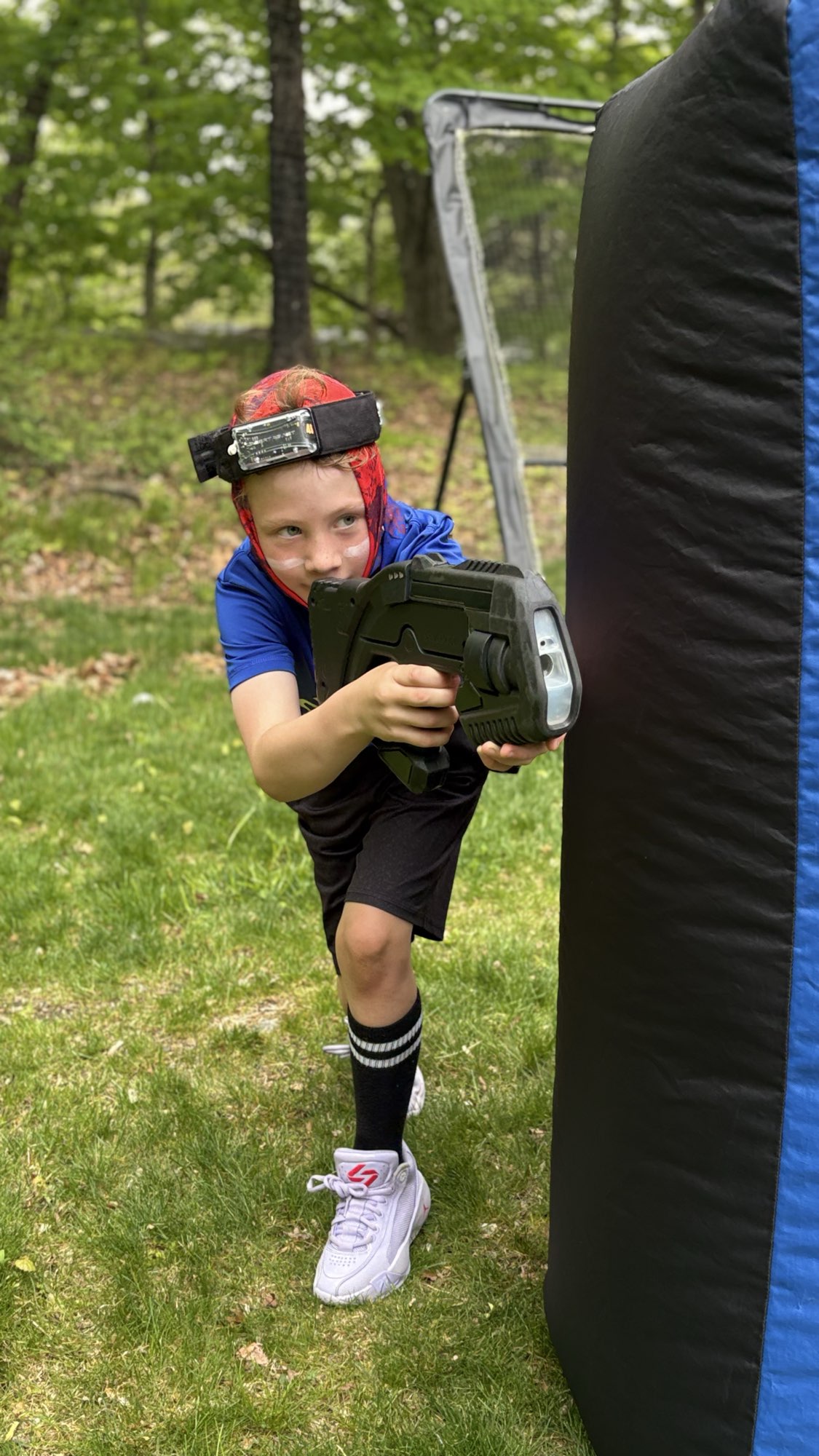 Young player taking aim from behind a mobile laser tag inflatable bunker during a birthday party