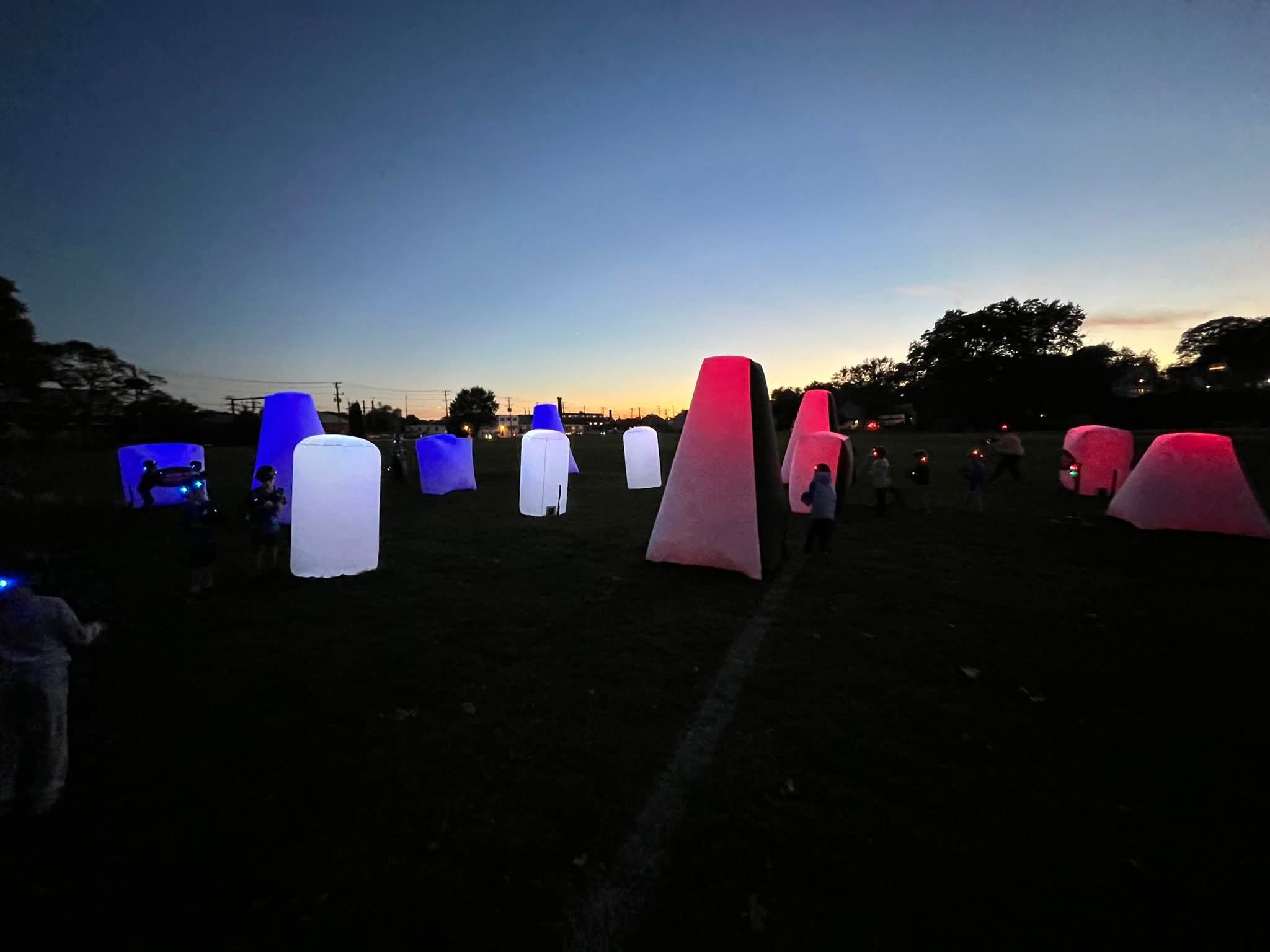 Outdoor Glow Course at Dusk — illuminated red, blue and white bunkers across an open field