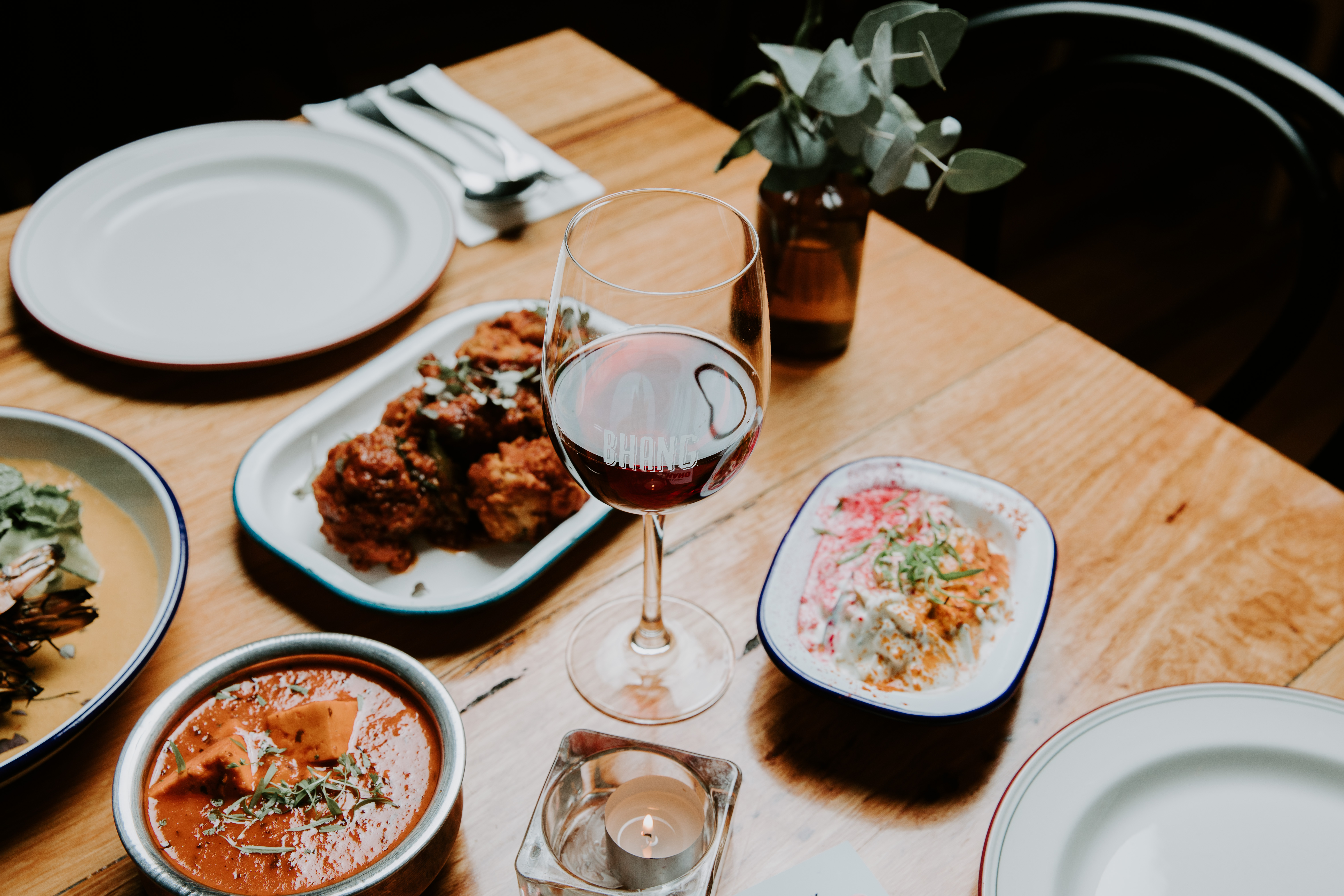 Hands sharing regional Indian dishes across the table at Bhang