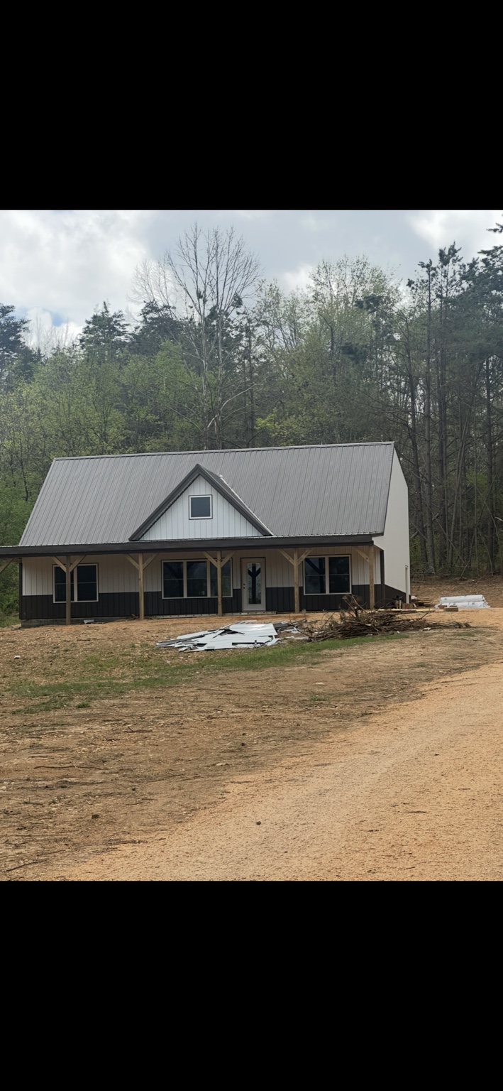 Completed custom home exterior with steep metal roof, dormer, and covered front porch
