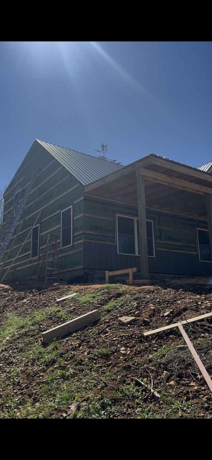 Joel Lindberg Residence — Side gable elevation showing window flashing, strapping, and porch roof framing under bright sun