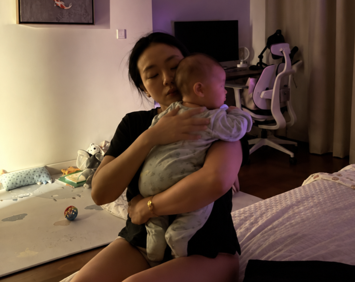 Jia holding baby Kai late at night in a dimly lit room