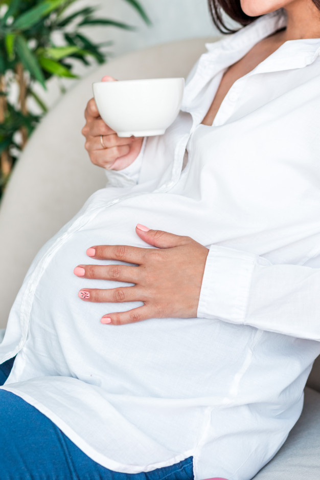 Mujer embarazada sentada disfrutando de una taza de té