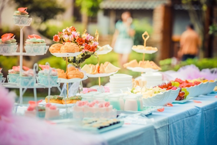 Mesa de tea party al aire libre con torre de bocadillos, cupcakes y dulces