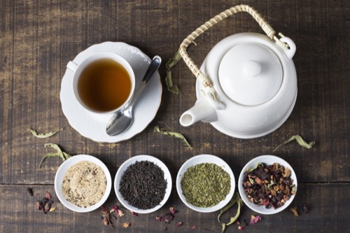 Selección de ingredientes botánicos secos aptos para tea blending junto a tetera y taza