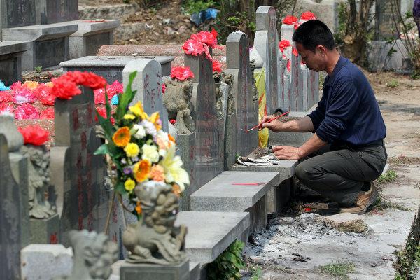 Limpieza y repintado de lápidas durante el día de QingMing en China