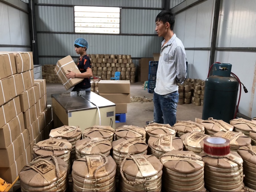 Pilas de discos de té Puerh (bing cha) empaquetados tradicionalmente en hojas de bambú y cajas para transporte