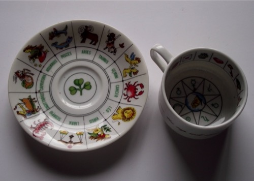 Taza y plato con símbolos zodiacales para la práctica de la taseomancia