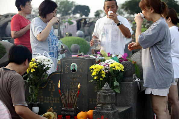 Familia bebiendo té frente a la tumba de sus antepasados durante QingMing