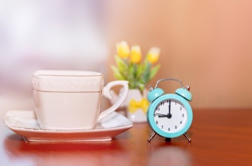 Taza de té y reloj despertador representando el tiempo de estabilización necesario del blend