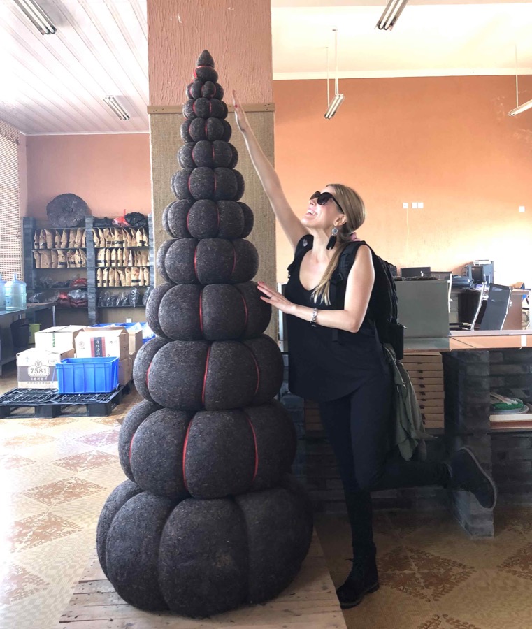 Victoria Bisogno junto a una pirámide gigante de té puerh comprimido que supera su altura