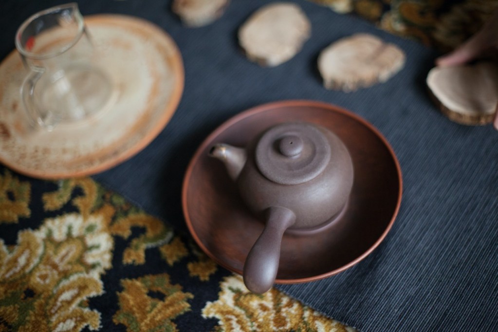 Tetera Zisha con asa lateral estilo kyusu tradicional en servicio de té sobre bandeja de madera