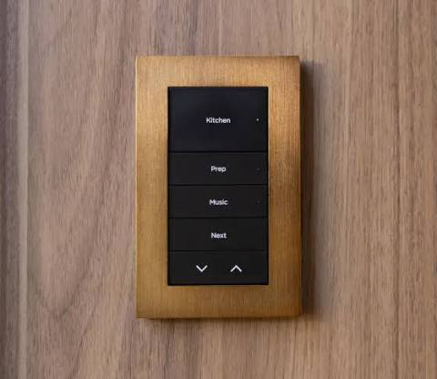 Control4 Lux keypad with brushed brass metal faceplate and custom engraved buttons set into walnut millwork