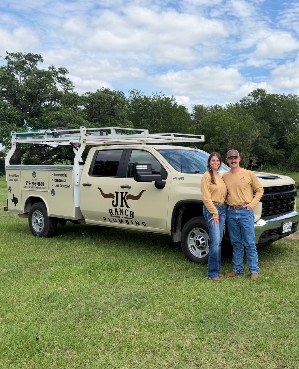 Owners Jacob Pryor and Julie Korenek standing by the JK Ranch Plumbing service truck with logo and license M-47091